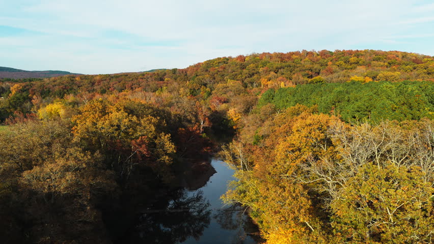 Winding river flowing through colorful autumn forest hills, upstream of Natural Dam Arkansas Ozark Mountains, drone dolly