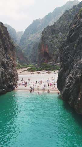 Aerial view of people enjoying the stunning natural beauty of Torrent de Pareis and Sa Calobra Beach, framed by dramatic cliffs and clear turquoise waters on Mallorca.