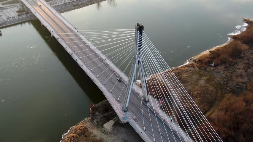 Świetokrzyski Bridge in Warsaw at sunset with city skyscrapers skyline, modern cable stayed bridge with traffic and warm golden light over urban landscape with Vistula River, Poland