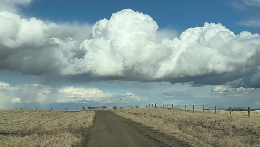 POV driving down scenic dirt road through open countryside with natural landscape and rural surroundings