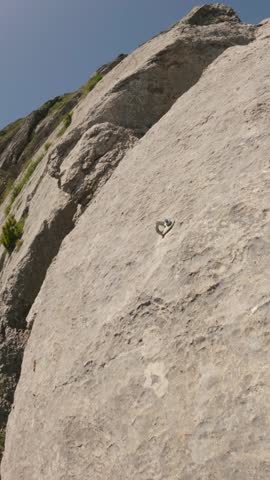 POV slow motion close-up of a climber clipping rope into a quickdraw on sunlit slab rock during a lead climbing ascent in bright natural light
