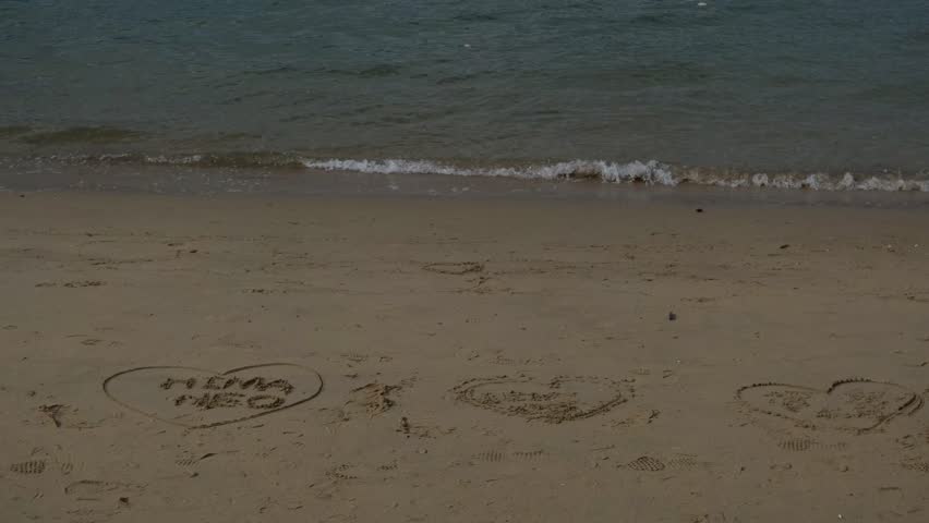 Calm Waves Approaching Sandy Beach with Drawings in Sand Peaceful Coastal Scene