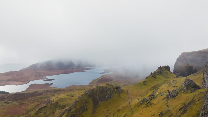 Aerial pullback shot reveals The Storr on the Isle of Skye in misty highland, Scotland