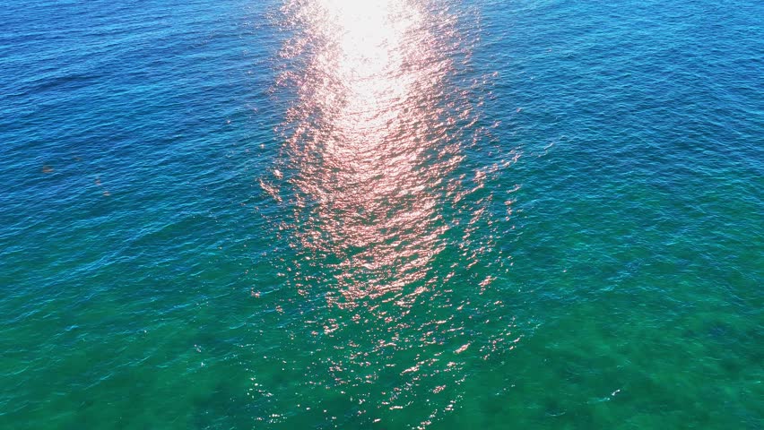 Atlantic Ocean on a sunny day. The sparkling seawater contrasts with the deep blue sea. A tranquil and minimalist seascape. Calm waters and a vast ocean landscape. Sunlight reflecting off the sea surface.