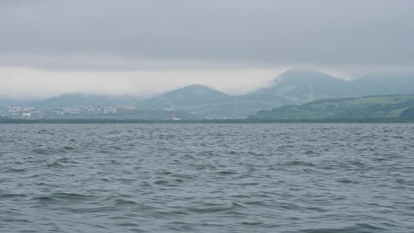 The city of Petropavlovsk-Kamchatsky and the waves of Avacha Bay in the Pacific Ocean in gloomy, cloudy, rainy weather.