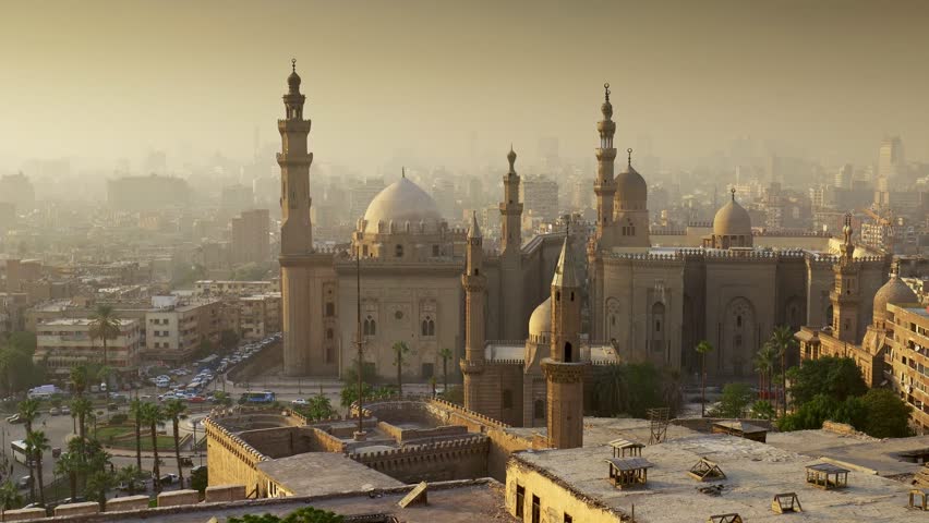 Majestic Sultan Hassan mosque in old Cairo, Egypt. Evening sunlight falls over the historic district of Cairo, Egyptian capital. Zoom out shot