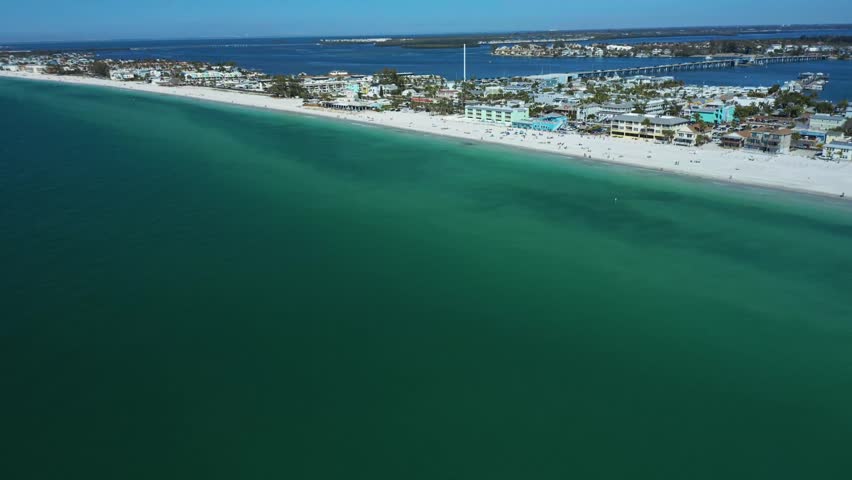 Stunning aerial footage showcasing a coastal beachfront with clear blue ocean waters and distant shoreline.
