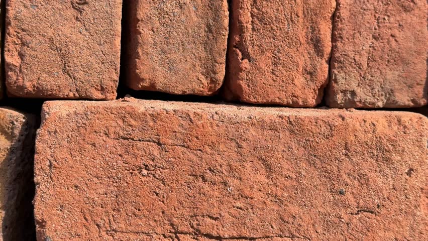 Close-up of stacked red bricks forming a textured wall background with natural patterns video