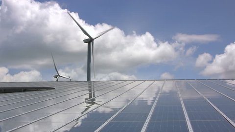 Giant wind turbine reflects on solar panels