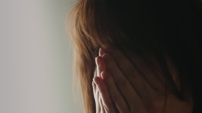 A close up of a tired and upset woman rubbing her face and eyes. She covers her face with her hands as she tries to relax and cope with stress.