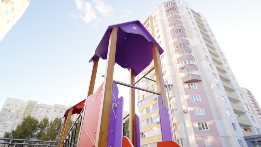 Bright tower with slide and ropes at children maze on playground. Funny kids attraction against multistory residential building low angle shot