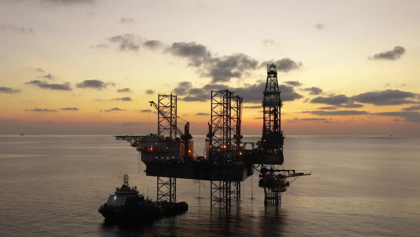 Aerial top view of offshore jack up rig and offshore platform during sunset for oil and gas exploration and production. 
