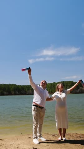 Pregnant couple celebrating gender reveal party with pink smoke