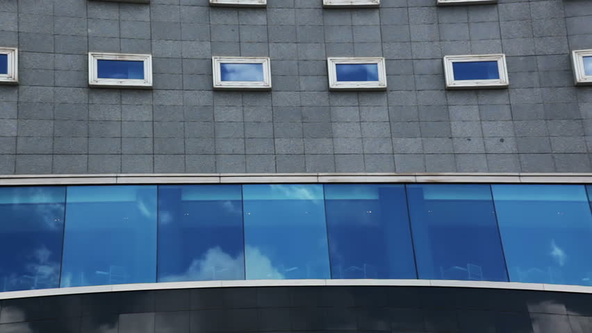 Office building. Clouds move fast and are reflected in the windows. Timelapse