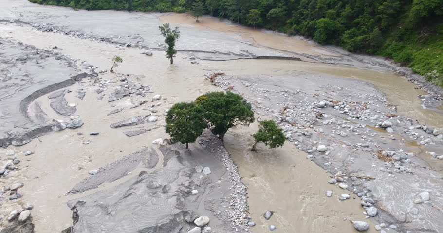 Drone shot of resilient trees standing within the Melamchi River after flood damage, surrounded by debris and altered river landscape in Sindhupalchowk Nepal.