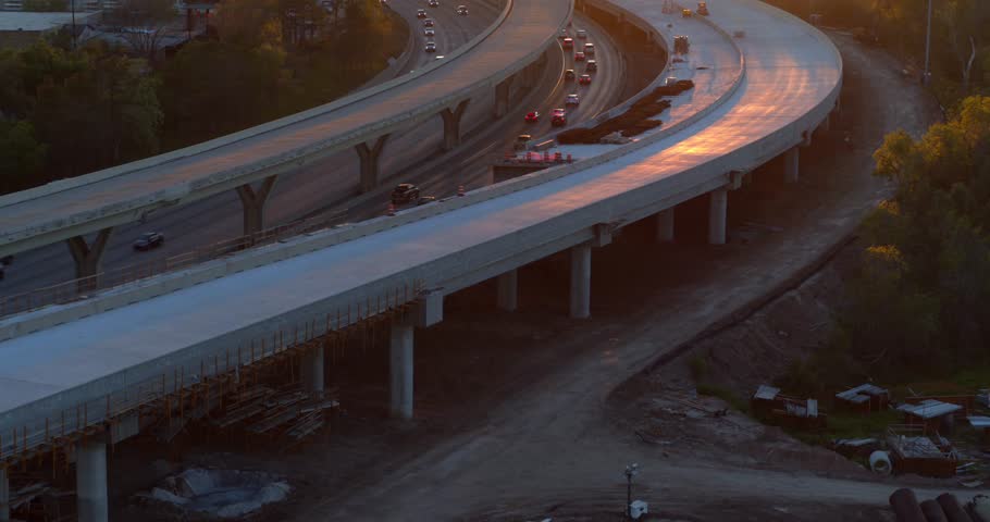 A stunning drone view of cars on the I-45 North freeway during sunset in Houston, Texas. The warm golden hour light bathes the highway as vehicles stream west