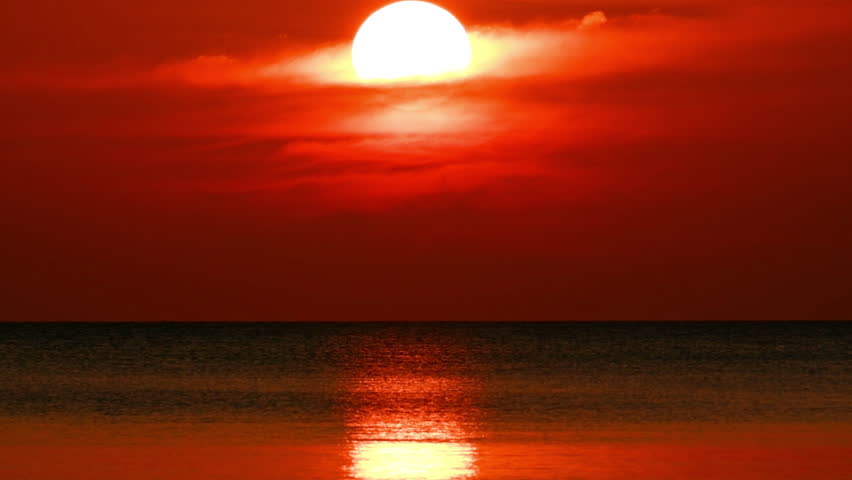 Time-lapse of sunset over the ocean horizon, colorful sky reflecting on the sea water.