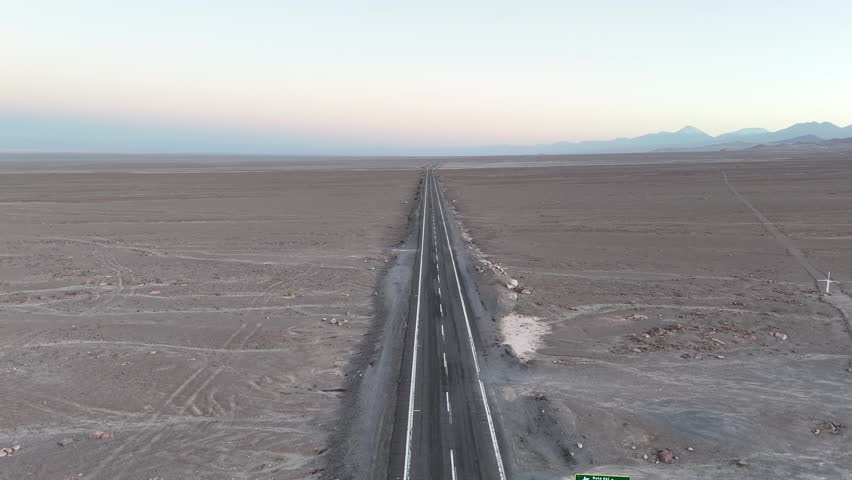 Cinematic aerial flying forward over the long, straight Ruta del Desierto (Highway 5) near the Tropic of Capricorn in the vast, arid landscape of northern Chile