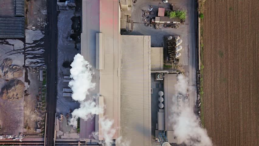 Aerial view of industrial buildings releasing plumes of smoke, contrasting with the surrounding landscape, Sremska Mitrovica, Vojvodina, Serbia.