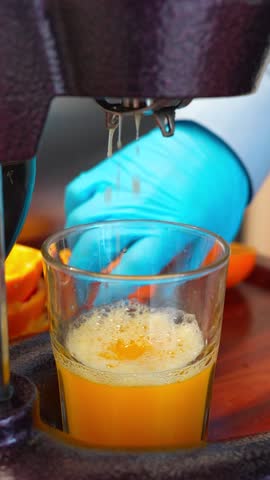 Vertical Close Up of Fresh Orange Juice Being Squeezed into Glass