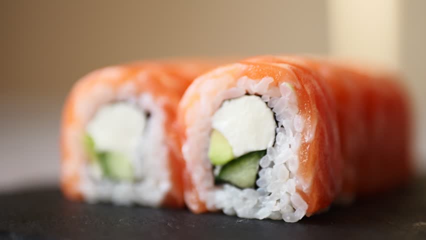 Delightful sushi rolls filled with cucumber and cream cheese elegantly displayed on a slate surface in a warm atmosphere.