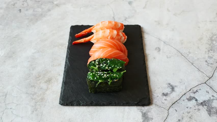 Exquisite sushi platter showcasing vibrant salmon, shrimp, and fresh greens on a sleek slate surface