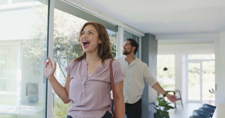 African American couple entering new home, woman holding red key fob, inspecting windows, hugging. Embrace, lifestyle, modern, minimalist, interior, plants, pendant