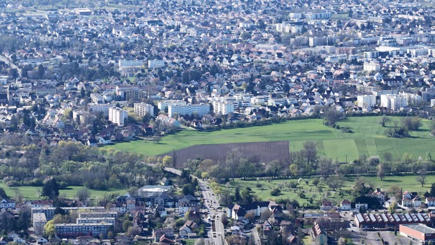 Aerial view of the urban landscape with buildings and green fields contrasting with each other, creating a picturesque scene, Sausheim, Grand Est, France.
