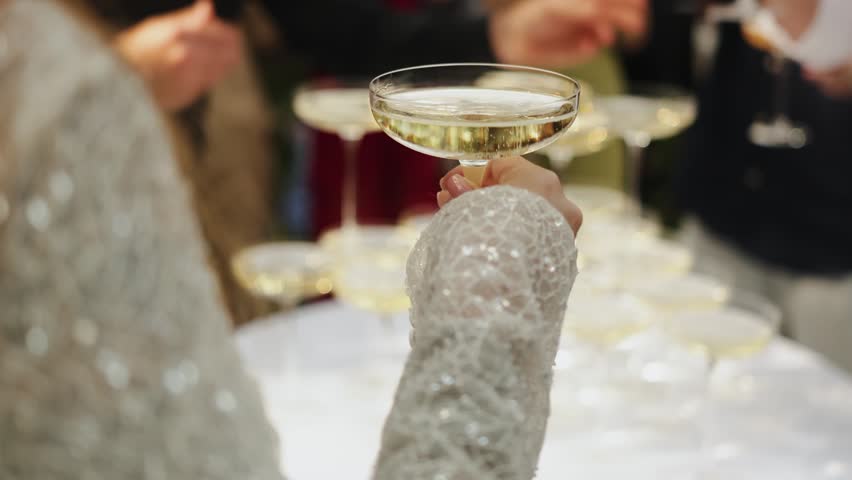 Bride Holding Champagne Coupe At Reception, Closeup Of Sequined Lace Sleeve Raising Sparkling Bubbly