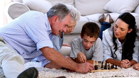 Extended family playing chess together on the floor at home