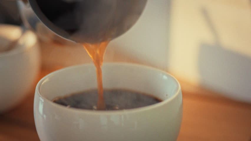 Morning sunlight streams over a cup of fresh coffee, its hot steam curling upward as the brew slowly cools, highlighting the quiet ritual of savoring a warm drink before the day begins