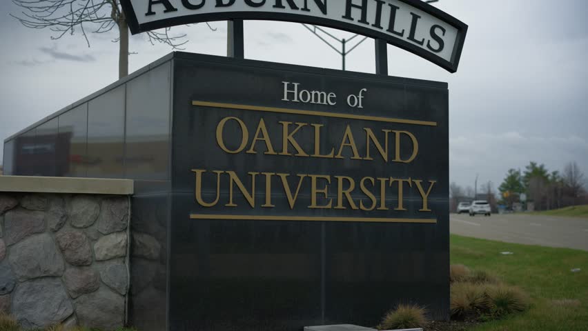 Pan left shot of sign and landscaping on the Oakland University campus in Auburn Hills Michigan in daylight with smooth cinematic motion