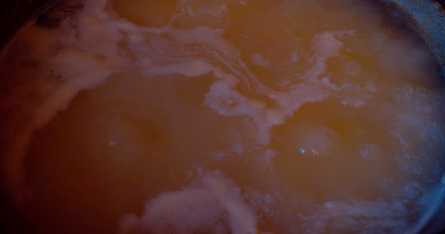 Macro shot of boiling meat broth in a pot.
