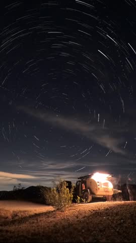 Vertical video, watch stars create trails above a teardrop camper in Anza Borrego Desert State Park, showcasing the beauty of the night sky.