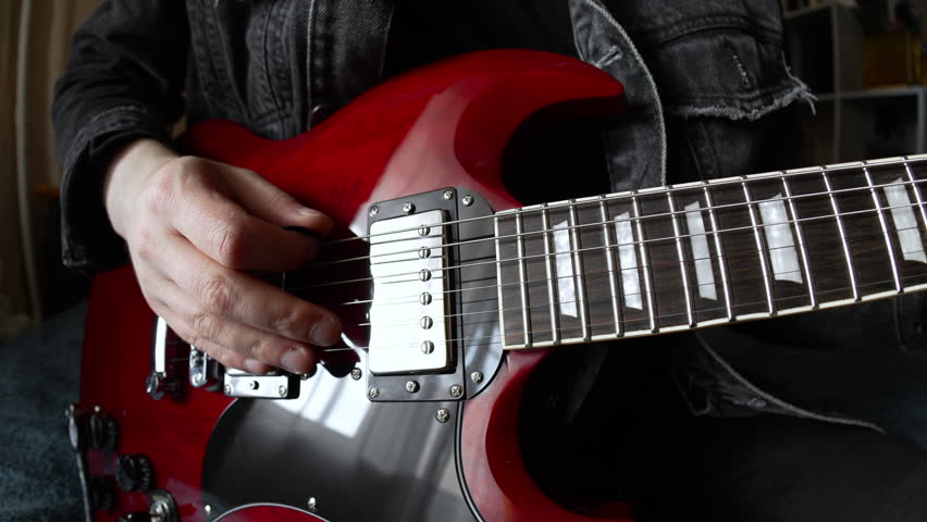 man in black denim playing electric red sg rock guitar in the day at home. Fisheye lens effect