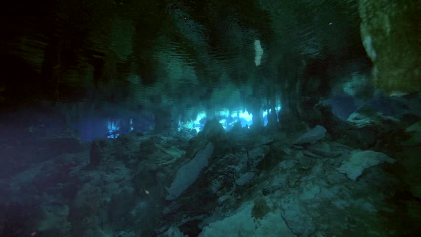 Reflected light shimmers under trapped air pocket while diver moves below in Cenote Dos Ojos, Quintana Roo, Mexico
