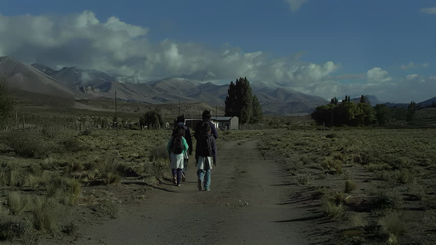 Group of children with backpacks walking towards a remote school