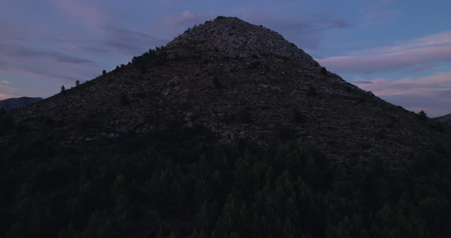 Rocky Mountain Summit At Dusk With Purple Twilight Sky, Granite Ridgeline And Scattered Boulders, Drone Aerial Revealing Remote Wilderness, Moody Cinematic Lighting,