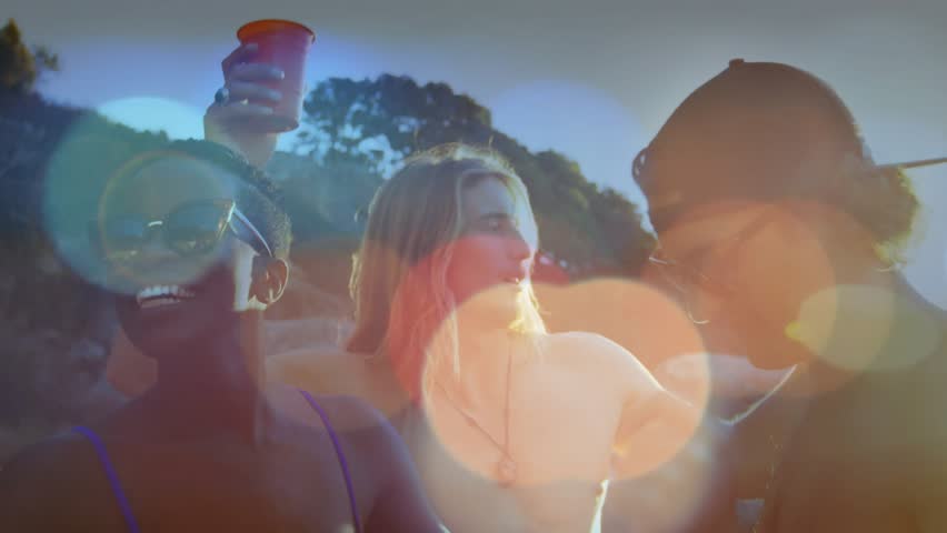 Travel crew mingling lead turning causing man in baseball cap leaning camera panning back red cups. Sunset, waterfront, beachside, friends, laughter, casual, sunglasses