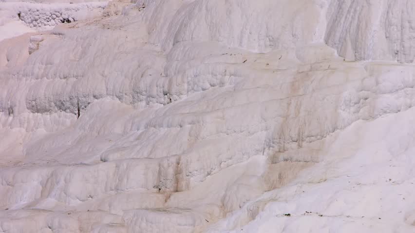 A captivating wide shot of the famous white calcium carbonate deposits and mineral-rich thermal pools in Pamukkale, Denizli Province, Turkey. This unique landscape, a UNESCO World Heritage Site, is a