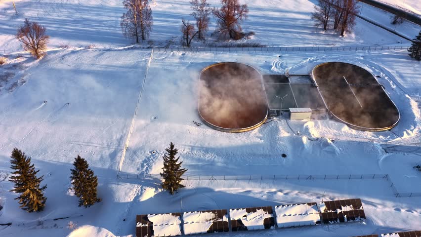 Aerial view of snowy park with misty ice rinks under clear sky