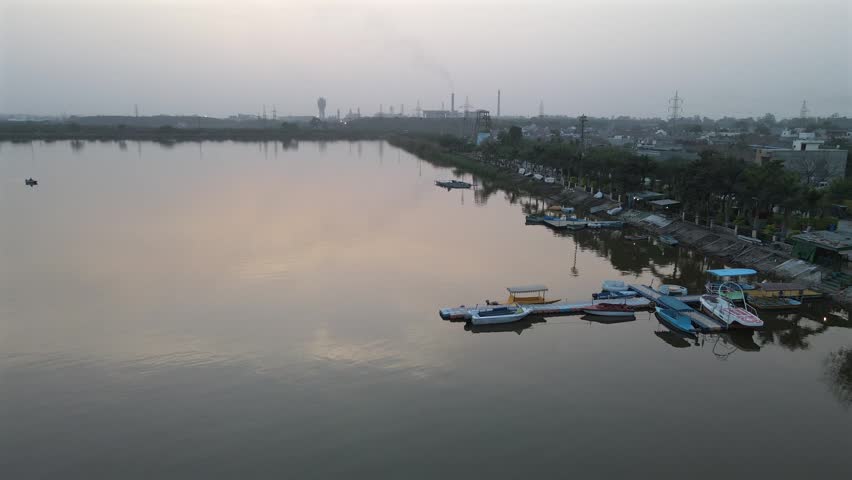 Peaceful Aerial Sunset over Bathinda Lake Boating Dock with Industrial Horizon.