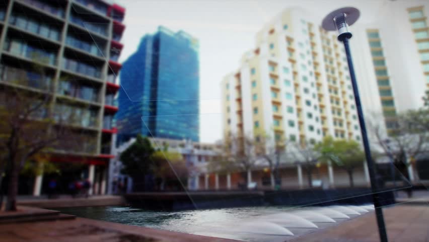 Reflective pool and water jets framing urban design plaza, play starting HUD gfx sliding over pool. Fountain, lamppost, benches, trees, courtyard, cityscape, skyline