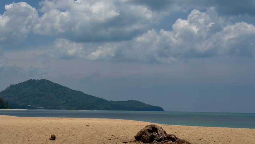 Scenic view of Mai Khao beach in Phuket, Thailand. Golden sand, blue sea, and green hills under a cloudy sky. Perfect tropical nature landscape for travel, vacation and adventure concepts