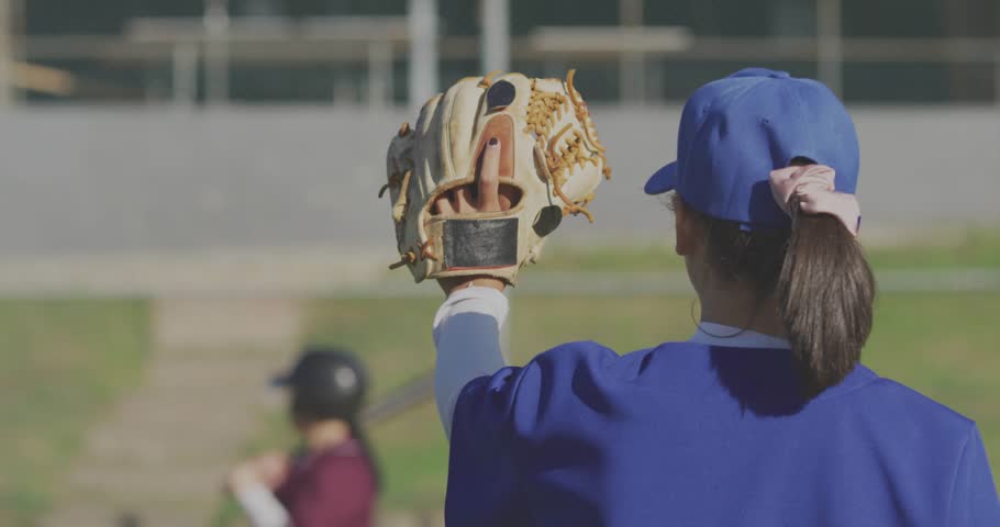 Female fielder raising glove on sports field, live feed overlays drifting displaying metrics. Baseball, defense, mitt, bat, ballpark, outdoors, graphics