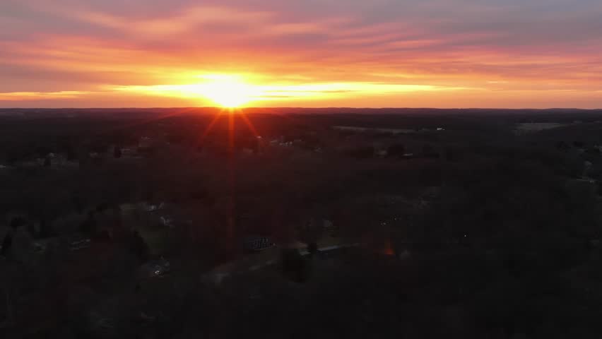 Dark forest trees in picturesque landscape of USA. Sunset time behind rural scenery of Virginia. Housing area with homes between forestry. Aerial wide shot. Quiet serene atmosphere. Dusk scene.