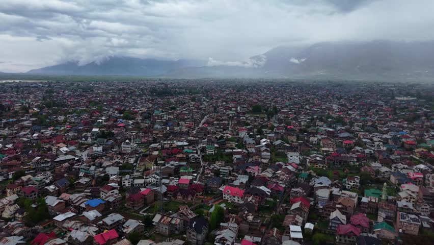 Aerial View of Cityscape with Distant Mountains, Aerial view of a vast residential area spread across a mountain valley.