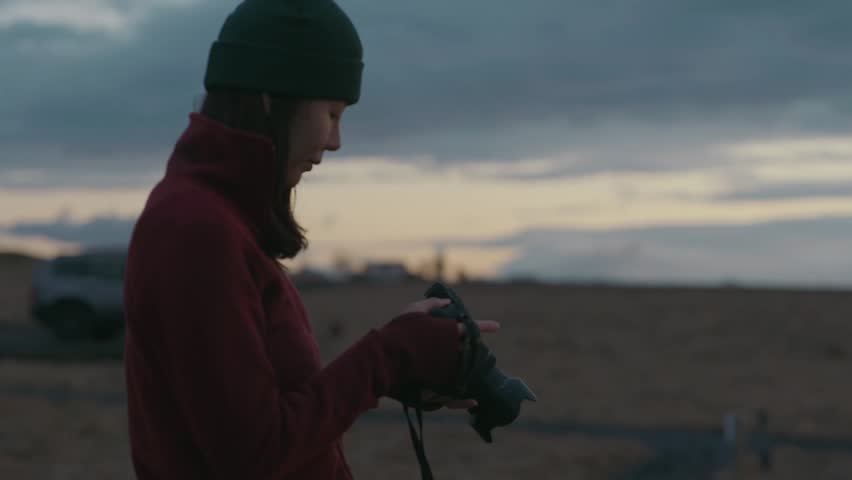 Close-up 4K footage of a dedicated photographer capturing moments in twilight, focusing and shooting.