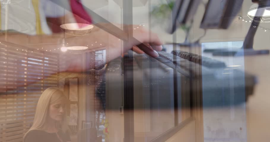 Right hand typing, keyboard closeup overlaying colleagues moving to screens updating office data. Workspace, monitors, desk, collaboration, minimalist, modern, lighting