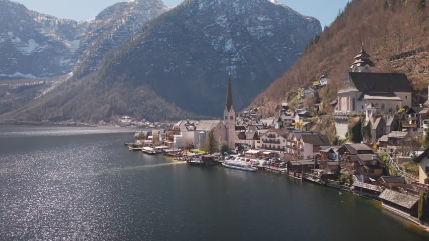 Aerial view of a picturesque lakeside village with traditional buildings and mountains.
